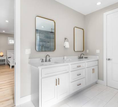 Freshen up in your pristine bathroom with dual vanities, elegant brass mirrors, and a spacious glass shower.