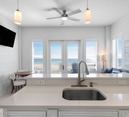Your bright kitchen features sleek countertops and stunning ocean views through expansive windows, perfect for morning coffee with sea breezes.