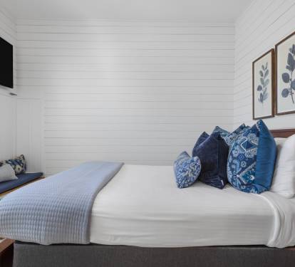 Sink into crisp white linens and plush blue pillows in your serene bedroom retreat, complete with coastal artwork and modern amenities.