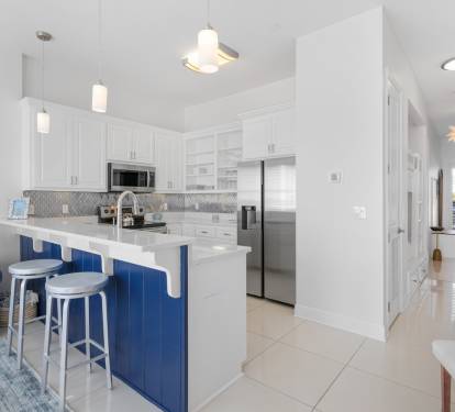Your fully-equipped kitchen with sleek white cabinets and vibrant blue island awaits your culinary adventures.