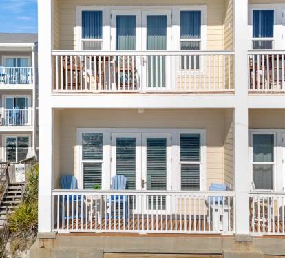 Gulf front property featuring multi-level balconies with coastal architecture and nearby vacation rental buildings.