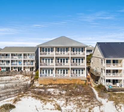 Gulf front rental complex featuring multiple vacation buildings with private balconies overlooking pristine white sand beaches.