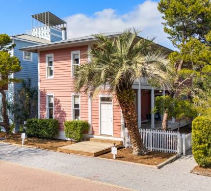 Charming coastal cottages nestled among palm trees and lush landscaping create a welcoming seaside retreat atmosphere.