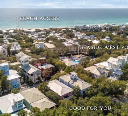 Aerial view of a charming beachside community with tree-lined streets leading to pristine white sand beaches and turquoise waters.