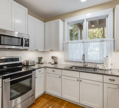 Your fully equipped kitchen awaits with granite counters, stainless appliances, and charming garden views through the window.