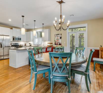 Your open-concept kitchen and dining space features modern appliances, granite countertops, and charming turquoise chairs around a spacious round table.