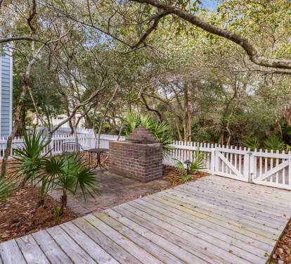 Relax on your private deck surrounded by lush coastal trees and tropical palms, with a charming brick fireplace for cozy evenings.