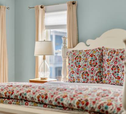 Drift off in your charming bedroom with floral linens and soft morning light filtering through cheerful curtains.