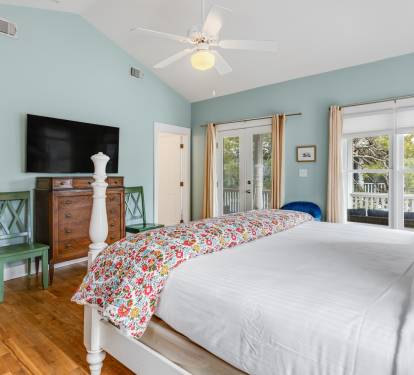 Drift off in your serene bedroom sanctuary with soothing mint walls, charming floral accents, and French doors opening to outdoor views.