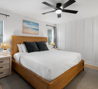 Rest peacefully in your serene bedroom with crisp linens, gentle ceiling fan breeze, and coastal artwork creating the perfect atmosphere.