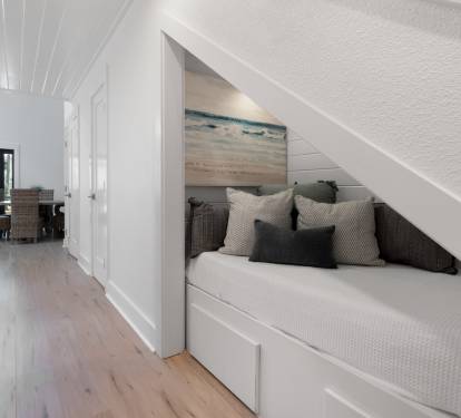 Cozy reading nook tucked beneath your stairs offers tranquil ocean views with plush cushions for lazy afternoons.