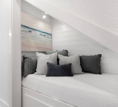 Cozy nook where you can unwind with soft textures and coastal charm tucked beneath the sloped ceiling.