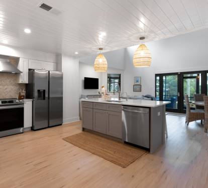 Gather with loved ones in this stunning open-concept kitchen featuring warm wood floors, pendant lighting, and stainless steel appliances.