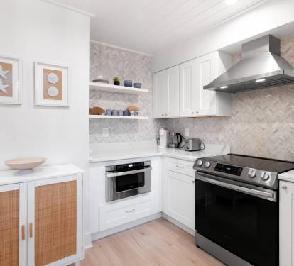 Your stylish kitchen features modern appliances, gleaming white cabinets, and herringbone marble backsplash—perfect for preparing memorable meals during your stay.