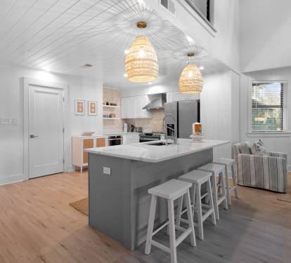 Your open-concept kitchen flows seamlessly into the living area, featuring a spacious island with bar seating under warm pendant lights.