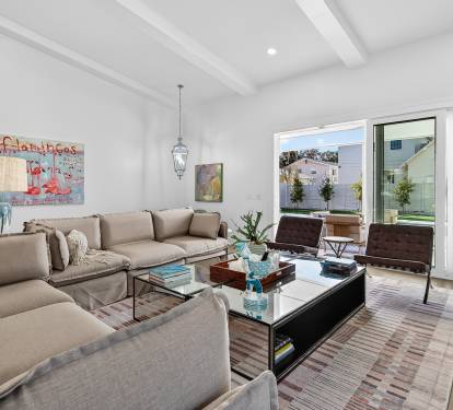 Sink into plush sofas beneath soaring beam ceilings in your bright, modern living space with floor-to-ceiling windows.