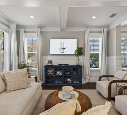 Unwind in your bright, coastal-inspired living space with plush seating and peaceful neighborhood views through every window.