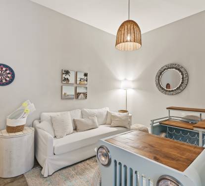 Unwind in your charming living space with coastal touches, a dartboard for entertainment, and warm lighting perfect for relaxing evenings.