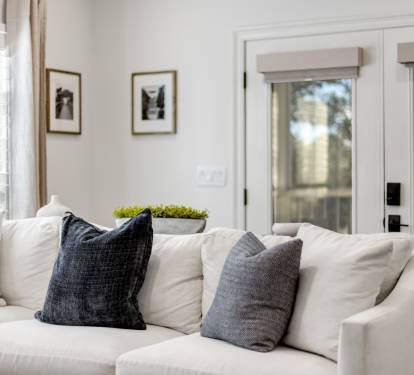 Sink into this plush white sectional where natural light streams through plantation shutters, creating your perfect afternoon reading nook.