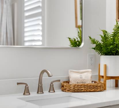 Freshen up in your stylishly appointed bathroom featuring a gleaming vanity, elegant fixtures, and thoughtful touches like fresh greenery.