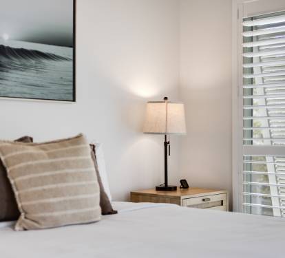 Sink into crisp white linens and plush pillows in your peaceful bedroom retreat, where ocean-inspired art creates tranquil vibes.