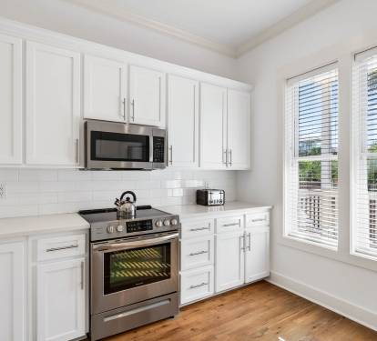 Your fully equipped kitchen features crisp white cabinets, stainless steel appliances, and warm hardwood floors, creating the perfect space for preparing home-cooked meals.