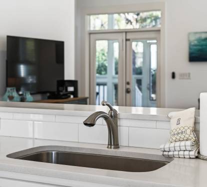 Your bright kitchen island invites cooking adventures with sleek quartz counters, undermount sink, and thoughtful touches like paper towels within easy reach.