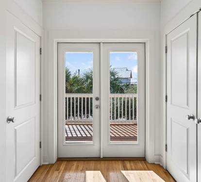 Step through these elegant French doors to your private balcony, where tropical palms and blue skies create the perfect backdrop for morning coffee.