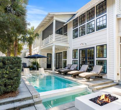 Elegant home features a private pool and fire pit surrounded by tropical landscaping for ultimate relaxation.