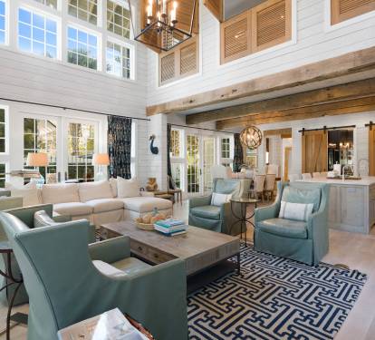 Relax in your spacious open-concept living area featuring soaring ceilings, rustic wooden beams, and comfortable seating perfect for gathering with loved ones.