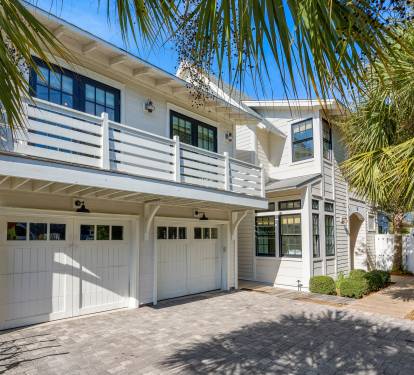 A stunning coastal-style home with palm trees and elegant architecture creates the perfect vacation retreat setting.