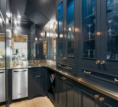 Step into your elegant butler's pantry with custom navy cabinetry, gleaming brass fixtures, and glass displays for your entertaining essentials.