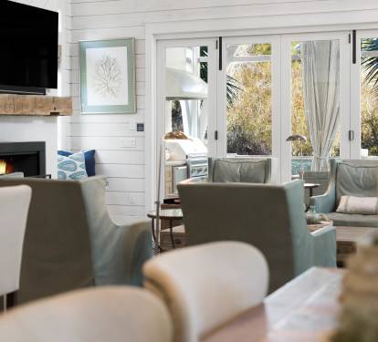 Relax in your bright living space with crackling fireplace, wall-mounted TV, and cozy seating overlooking tropical gardens.
