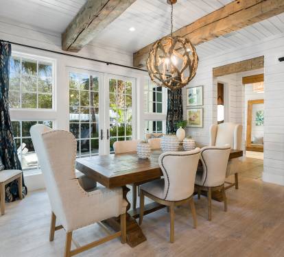 Gather around this elegant dining table where rustic beams meet coastal charm, creating the perfect backdrop for memorable meals.