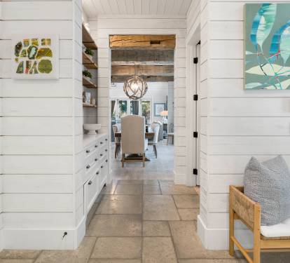 Relax in your bright coastal retreat with shiplap walls, artistic touches, and cozy seating flowing into dining spaces.