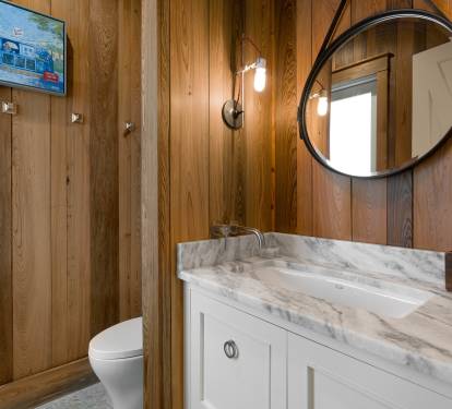 Unwind in your elegant bathroom featuring warm wood walls, marble countertops, and modern fixtures for your comfort.