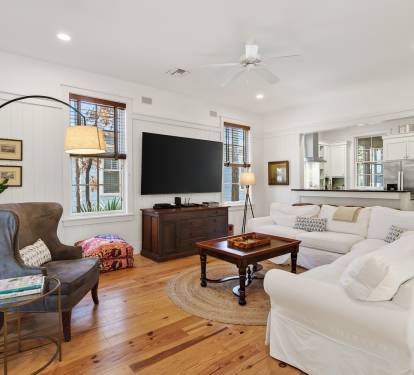 Sink into the plush white sectional sofa and unwind in this light-filled living space with gleaming hardwood floors and thoughtful touches.