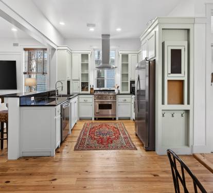 Your gourmet kitchen invites culinary adventures with premium appliances, spacious counters, and charming vintage rug on warm hardwood floors.