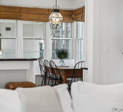 Gather around your bright dining nook where natural bamboo shades frame windows and elegant lighting creates the perfect ambiance for memorable meals.