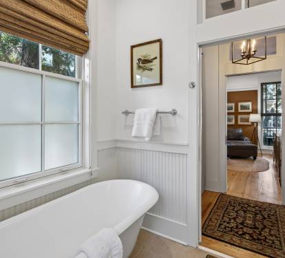Your private bathroom sanctuary features a soaking tub where you can unwind while natural light streams through bamboo blinds.
