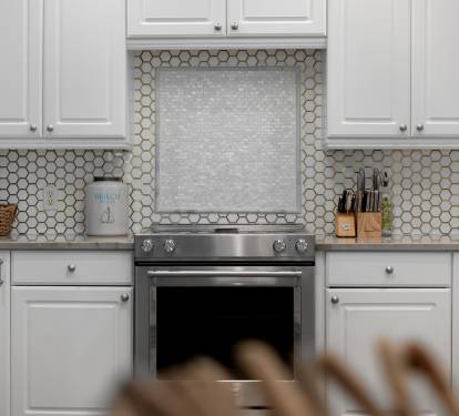 Your gourmet kitchen awaits with pristine white cabinets, stylish hexagonal backsplash, and premium stainless steel appliances ready for culinary adventures.