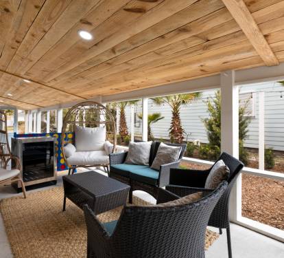 Settle into your private covered patio where rustic wood beams frame comfortable seating and cooling fans create the perfect outdoor retreat.