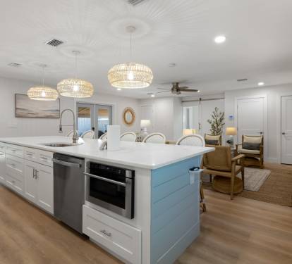 Gather around your spacious kitchen island where coastal pendant lights cast a warm glow over marble countertops, perfect for morning coffee or evening conversations.