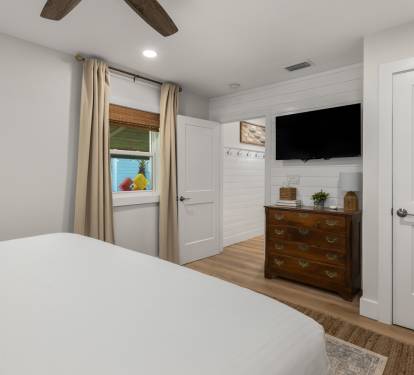 Drift off to sleep in your peaceful bedroom featuring rustic wood beams overhead, a mounted TV for evening relaxation, and warm touches throughout this inviting space.