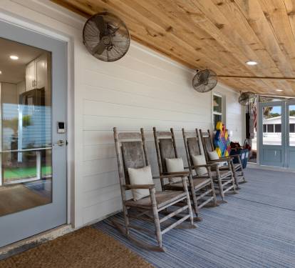 Unwind in your charming covered porch with rustic rocking chairs, where gentle ceiling fans create the perfect atmosphere for morning coffee or evening relaxation.