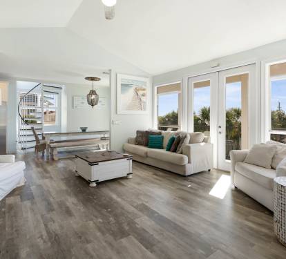 Sink into plush white sofas bathed in natural light, where floor-to-ceiling windows frame peaceful treetop views for your perfect getaway.