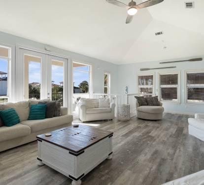 Relax in your bright, airy living room with plush seating and stunning coastal views through expansive windows.