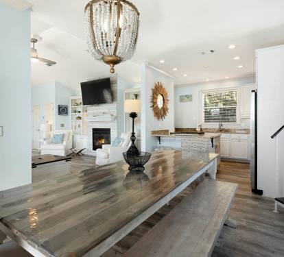 Gather around this stunning farmhouse dining table where memories are made beneath elegant crystal lighting.