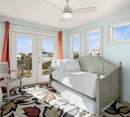 Relax in your bright coastal retreat with serene blue walls, comfy daybed, and French doors opening to your private balcony.