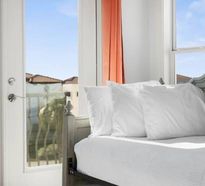 Wake up to crisp white linens and sunny views from your bright bedroom balcony doors.